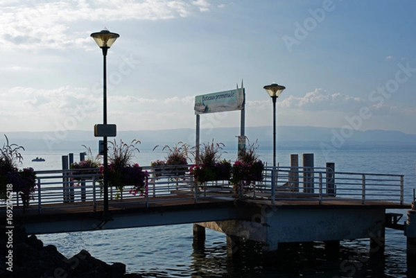 Obraz Ponton en bois sur un lac au soleil couchant en fin de journée de vacances d'été. Embarcadère pour bateau de croisière et navette maritime.