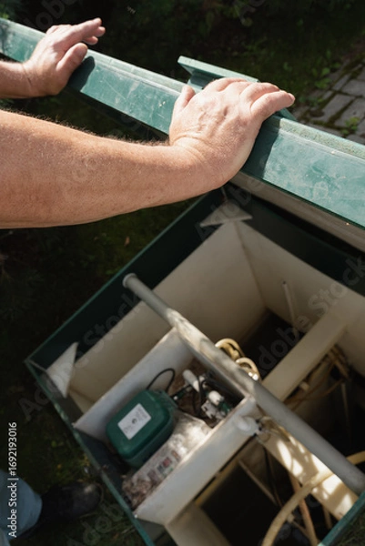 Obraz Man checking modern septic tank system outdoors.
