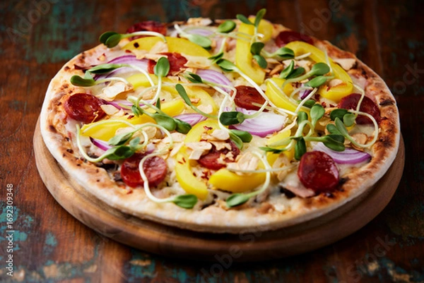 Fototapeta Pizza with chorizo ​​sausage, mozzarella cheese and yellow pepper. Rustic wooden background. Soft focus.