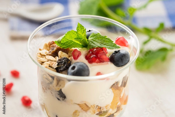 Obraz Cup of breakfast healthy muesli with blueberries, seeds of pomegranate and yogurt.