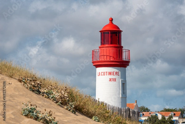Obraz La Cotinière Lighthouse behind sand dune on a sunny day in summer. Beautiful red and white french lighthouse located in La Cotinière, Oléron island, Charente-Martime in France.