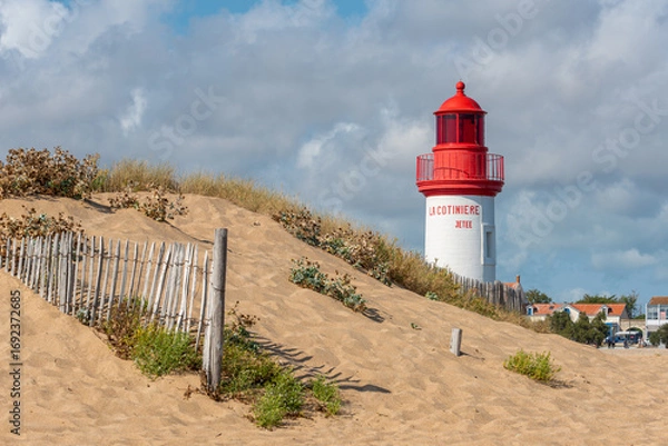 Obraz La Cotinière Lighthouse behind sand dune on a sunny day in summer. Beautiful red and white french lighthouse located in La Cotinière, Oléron island, Charente-Martime in France.
