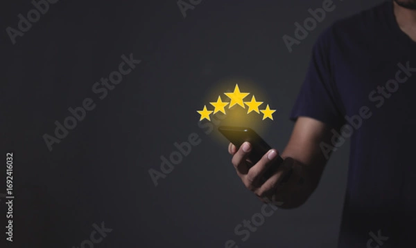 Fototapeta Review Customer, Young Man hand holding Smart Phone with five star to review and give 5 stars with very good results in service, Good review 5 star rating choice feedback
