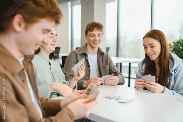 Fototapeta Happy college students playing cards in the university break room