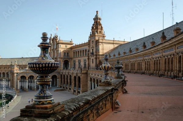 Fototapeta A high-angle shot captures the stunning architecture of the Plaza de España in Seville, Spain. The focus is on the ornate ceramic balustrade in the foreground, leading the eye towards the building
