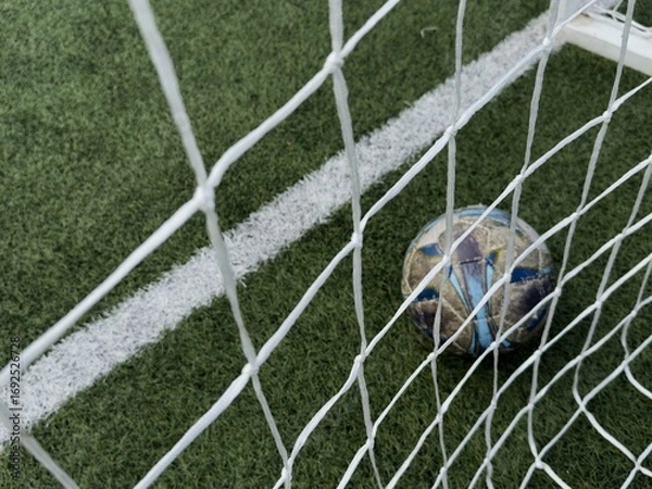 Fototapeta textured soccer game field with ball in front of the soccer goal - soccer ball in soccer net.