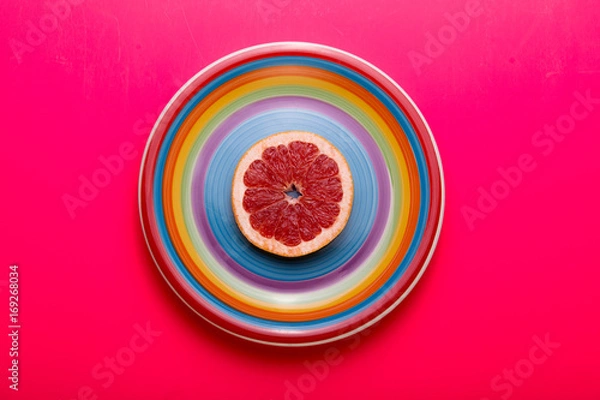Fototapeta Red grapefruit slice on plate. Flat lay.