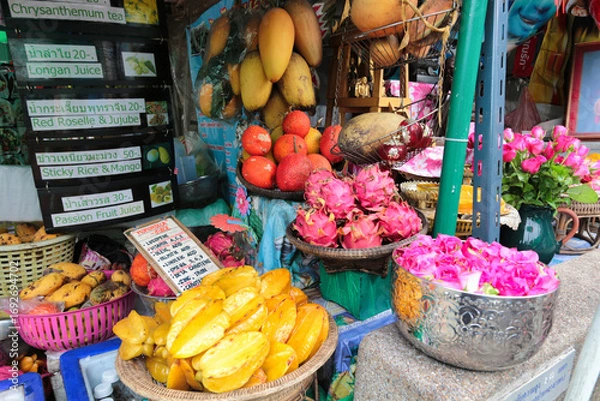 Obraz Vibrant Thai market fruit stand - A colorful display of fresh tropical fruits like starfruit, dragon fruit, and mango at a local market stall in Thailand.