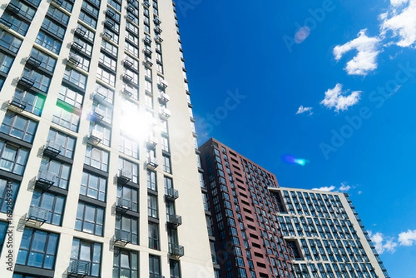 Fototapeta Tall, modern high-rise residential buildings with many windows and balconies on a sunny day with a deep blue sky