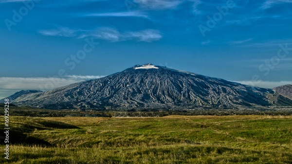 Obraz Panoramic view of black volcano Snæfellsjökull with blue sky above and green dry grass below . West Iceland, Europe.