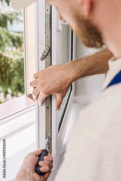 Fototapeta Repairman installs PVC window frame for improved energy efficiency