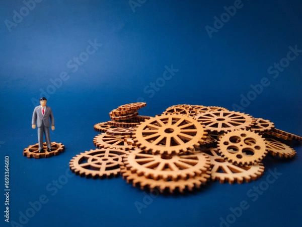 Fototapeta The miniature figure on a single gear represents an individual or a small part of a larger operation