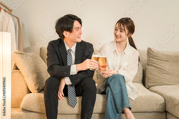 Fototapeta 夜,帰宅後にソファに座りながらビールを飲む若いアジア人夫婦,カップル
