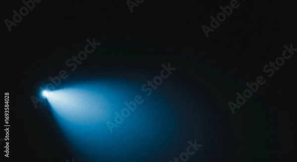 Fototapeta A bright blue light beam illuminates a dark empty space with soft atmospheric glow