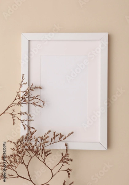 Fototapeta Mockup of white photo frame with dry grass on beige background. Top view