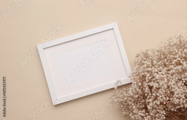Fototapeta Mockup of white photo frame with dry grass on beige background