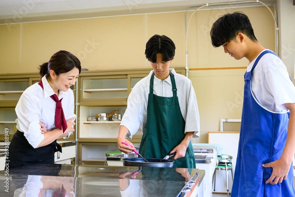 Fototapeta 料理教室で学ぶ男子学生と女性講師　料理レッスン風景