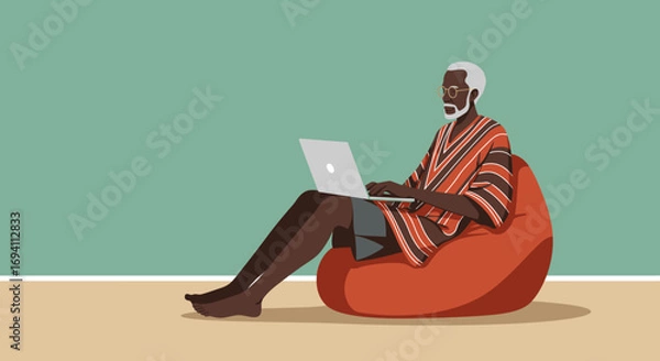 Fototapeta Elderly African man comfortably working on a laptop from a bean bag chair at home, embodying modern remote work and digital lifestyle.
