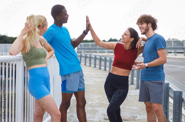 Fototapeta Smiling group of people are preparing for running together talking and stretching on outdoor road.
