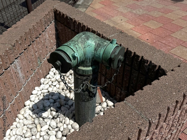 Fototapeta Fire hydrant - connection point for firefighting equipment. Urban safety concept. Handmade phone photo, selective focus, harsh sunlight, non AI
