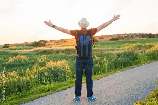 Fototapeta Man with arms raised, looking out over field