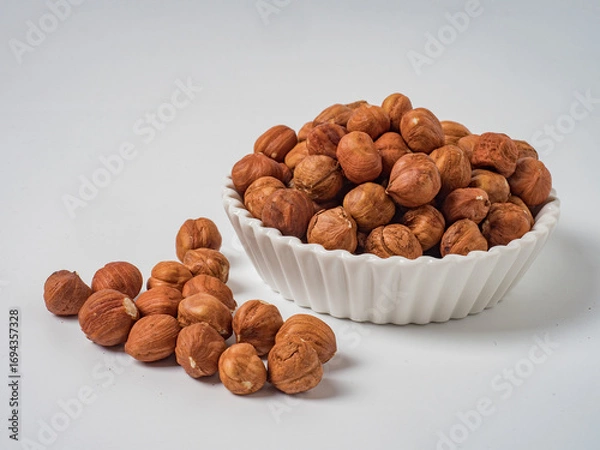 Obraz Raw hazelnuts without shells in a bowl on a white background
