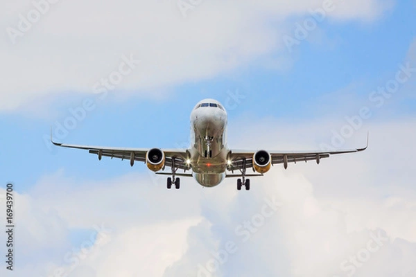 Fototapeta airplane flying overhead - landing / takeoff - blue sky with clouds