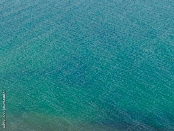 Fototapeta Aerial view of a calm, turquoise sea. A serene and minimalist background perfect for travel, wellness, or abstract design concepts.