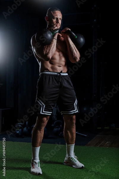 Obraz Muscular man having training with weights. Strong athletic man does workout. Concept bodybuilder doing exercises in gym.