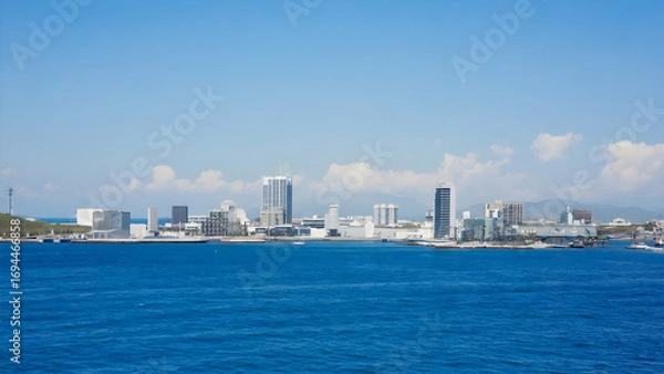 Fototapeta Scenic ocean view of a cityscape with modern buildings under a clear blue sky during daytime