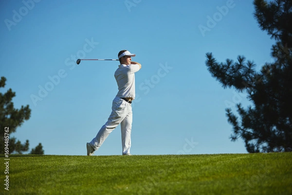 Fototapeta Golfer completing dynamic swing on sunny golf course. Concept of active lifestyle, motivation, physical discipline, leisure, and sports balance.