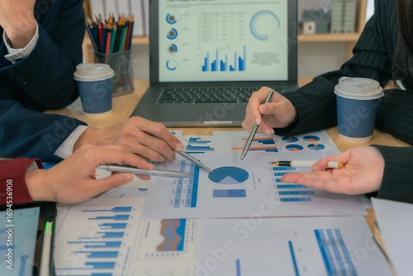 Fototapeta Business team analyzes financial data in meeting, discusses company reports, uses charts for analysis, brainstorming, planning and strategy. Close-up.