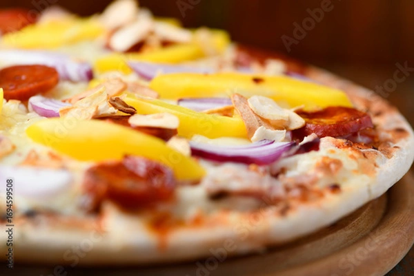Fototapeta Pizza with chorizo ​​sausage, mozzarella cheese, yellow pepper and black olives. Rustic wooden background. Soft focus.	