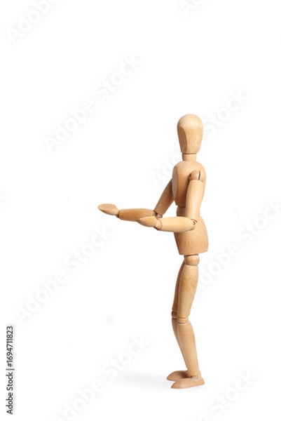 Fototapeta A wooden toy mannequin doing holding gesture isolated on a white background with copy space