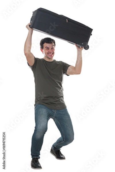 Fototapeta Furious and irritated young man traveler lifting and throwing away his travel luggage. Displeased guy has issues with his baggage, full length portrait isolated on transparent background
