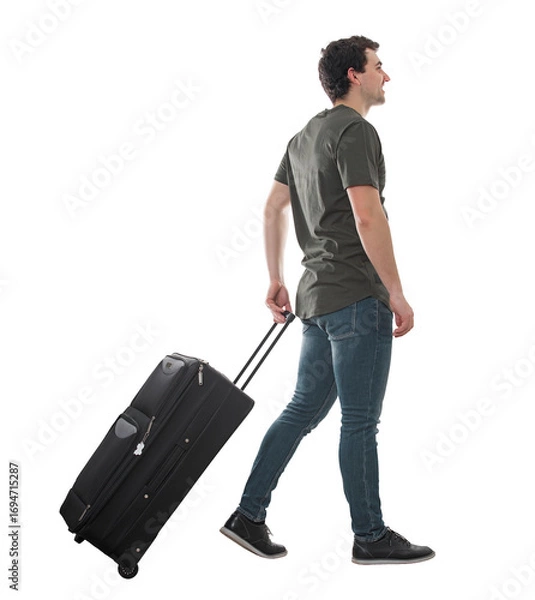 Fototapeta Side view guy traveler carrying his rolling suitcase, walking isolated on transparent background. Full length male tourist with luggage