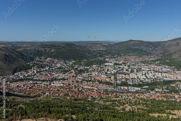 Fototapeta aerial view of city of mostar bosnia with dinaric alps at horizon with many colorful houses and river passing by in summer landscape