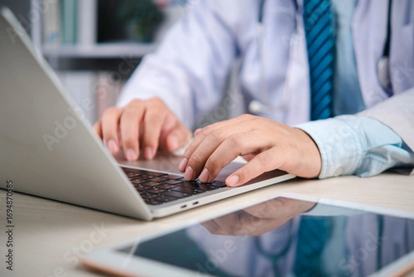 Obraz Medical doctor working on laptop in hospital patient records and communicate via telehealth, technology medicine, data security, and modern care. concept telehealth productivity