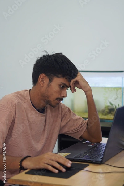 Fototapeta Stressed Man Holding Head While Working on Laptop in Office