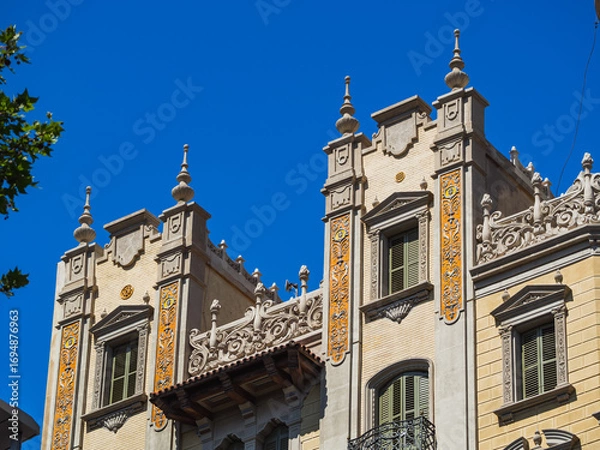 Fototapeta Historic building facade with decorative towers and Gothic revival architecture under blue sky