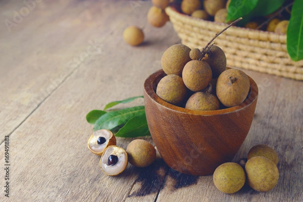 Fototapeta Fresh longan fruit with peel the skin show white meat and black seed on a wooden background.
