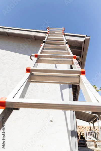 Fototapeta ladder leaning against a roof of a home