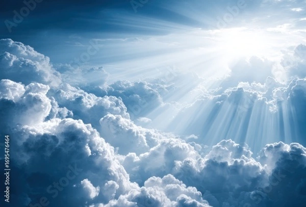 Obraz A radiant sunbeam filters through fluffy, billowing clouds in a bright, blue sky creating a sense of hope and ethereal beauty