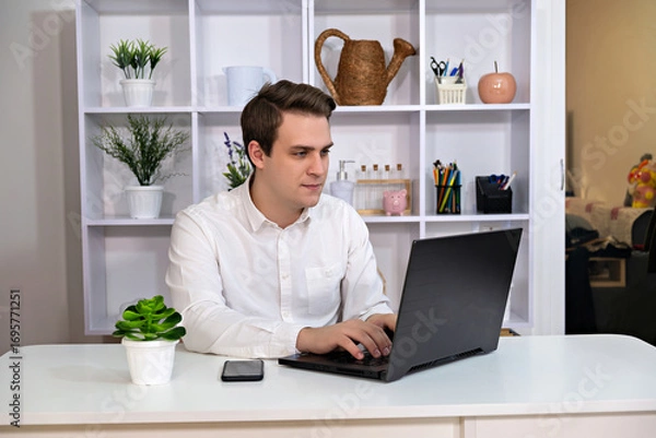Fototapeta In the image there is a person sitting at a desk with a laptop
