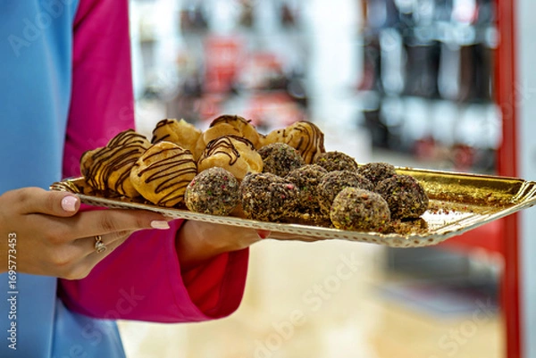 Fototapeta In the image you can see a person holding a tray with a variety of desserts