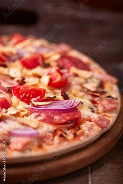Fototapeta Pizza with ham, salami, cherry tomatoes and mozzarella cheese. Rustic wooden background. Soft focus. Close up.	