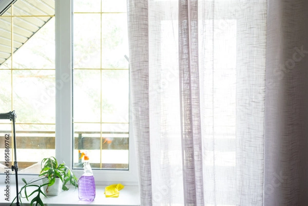 Fototapeta Window cleaning products are lying on the windowsill with a rag, spray, detergent. Spring cleaning in the house, cleaning service