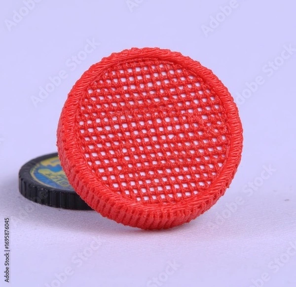 Fototapeta Red plastic circular lid with a woven mesh pattern