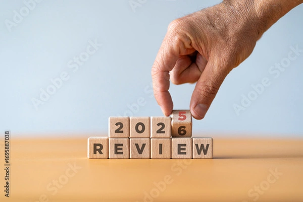 Fototapeta Hand flipping of 2025 to 2026 on wooden blocks. 2025 business and customer review for business strategic planning in the next year 2026. End of the year business concept.