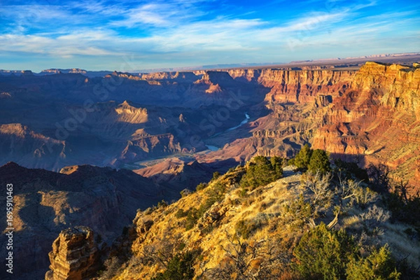 Fototapeta Grand Canyon at sunset viewed from Desert View Watchtower, showcasing vibrant canyon walls and the Colorado River winding through the landscape.